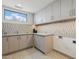 Well-lit laundry room with stone countertops, mosaic backsplash, custom cabinets, and tile flooring at 37200 N Cave Creek Rd # 1013, Scottsdale, AZ 85262