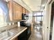 Well-lit kitchen featuring wooden cabinets and black appliances with access to dining area at 381 S Gypsum Dr, Apache Junction, AZ 85119