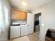 Bright laundry room with window, wooden cabinets, and a modern washer and dryer set at 381 S Gypsum Dr, Apache Junction, AZ 85119