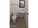 Practical powder room featuring a pedestal sink, toilet, mirror, towel bar, and tile flooring at 5311 W Fulton St, Phoenix, AZ 85043