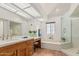 Bright bathroom featuring double sinks, a built-in vanity, soaking tub, and glass-enclosed shower at 9204 N 106Th Way, Scottsdale, AZ 85258