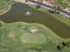Aerial view of a golf course with a scenic pond featuring a fountain and meticulously manicured greens at 9847 E Michigan Ave, Sun Lakes, AZ 85248