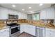Well-appointed kitchen with stainless steel appliances, granite counters, white cabinetry, and ample natural light from the window at 9847 E Michigan Ave, Sun Lakes, AZ 85248
