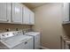 Laundry room area with a washer, dryer, and white cabinets above at 9847 E Michigan Ave, Sun Lakes, AZ 85248