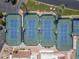 Aerial view of tennis courts featuring well-maintained blue courts, professional lighting, and lush landscaping around the perimeter at 9847 E Michigan Ave, Sun Lakes, AZ 85248