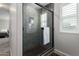 Modern shower featuring glass doors, dark tile, a shower niche, and stylish fixtures at 10983 W Mckinley St, Avondale, AZ 85323
