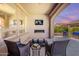 Covered patio with fireplace and television at dusk with patio furniture at 132 E El Prado Dr, Queen Creek, AZ 85140