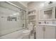 Well-lit bathroom showcasing a shower over tub, white vanity with storage, and open shelving at 1529 W Wickieup Ln, Phoenix, AZ 85027