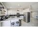 Bright kitchen featuring white cabinets, stainless steel appliances, breakfast bar with stylish seating, and modern black backsplash at 1529 W Wickieup Ln, Phoenix, AZ 85027
