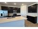 Open kitchen with stainless appliances, breakfast bar, and modern dark cabinetry at 15773 W Beryl Ave, Waddell, AZ 85355