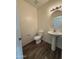 A half bathroom features a pedestal sink and toilet, illuminated by modern vanity lighting at 1734 W Pollack St, Phoenix, AZ 85041