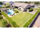 Aerial view of a home with large backyard, lush green lawn, covered patio, and sparkling pool at 17673 E Bronco Dr, Queen Creek, AZ 85142
