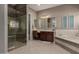Bright bathroom featuring a glass-enclosed shower and vanity with sink, and a soaking tub at 17673 E Bronco Dr, Queen Creek, AZ 85142