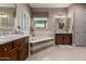 Elegant bathroom featuring a soaking tub, dual vanities with dark wood cabinets and tile flooring at 17673 E Bronco Dr, Queen Creek, AZ 85142