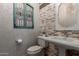 This powder room includes a pedestal sink, decorative mirror, stone accent wall and interesting wall decor at 17673 E Bronco Dr, Queen Creek, AZ 85142