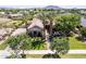Aerial view of a single story home with palm trees, green lawn and mature landscaping in a residential neighborhood at 17673 E Bronco Dr, Queen Creek, AZ 85142