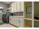 Well-organized laundry room with washer, dryer, cabinets, sink, and open shelving at 17673 E Bronco Dr, Queen Creek, AZ 85142