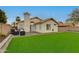 Well-manicured backyard featuring green turf, a covered patio, and desert landscaping at 21940 N 69Th Dr, Glendale, AZ 85310