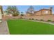 Expansive backyard with artificial turf, mature landscaping, and a concrete block fence at 21940 N 69Th Dr, Glendale, AZ 85310