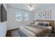 Bright bedroom featuring a cozy bed, two windows, and decorative botanical prints at 26733 W Melinda Ln, Buckeye, AZ 85396