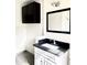 Bathroom with white vanity, black countertop, framed mirror, and dark wall cabinet at 2925 N 19Th Ave # 97, Phoenix, AZ 85015