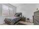 Neutral bedroom with a bed, gray comforter, and a nightstand illuminated by natural light from a window at 31318 N 26Th Dr, Phoenix, AZ 85085