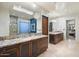 Bathroom with a large mirror, dual sinks, wooden cabinets, and a glass-enclosed shower at 39254 N 104Th Pl, Scottsdale, AZ 85262