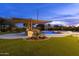 Twilight view of swimming pool, outdoor kitchen with pergola and a rock waterfall feature at 4547 S Banning Dr, Gilbert, AZ 85297