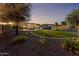 Expansive backyard featuring a stunning pool with rock accents, lush green lawn, mature trees, and beautiful landscaping at 4547 S Banning Dr, Gilbert, AZ 85297