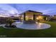 Beautiful outdoor kitchen under a pergola, next to a custom designed swimming pool with waterfall feature at twilight at 4547 S Banning Dr, Gilbert, AZ 85297