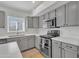 Modern kitchen with gray cabinetry, stainless steel appliances, quartz countertops, oven and tile floors at 515 W Smoke Tree Rd, Gilbert, AZ 85233