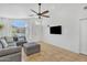 Bright living room with large sofa, tile floors, white walls, ceiling fan, wall mounted tv and natural light at 515 W Smoke Tree Rd, Gilbert, AZ 85233