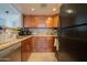 A modern kitchen with wood cabinets, tile backsplash, and black appliances at 7126 N 19Th Ave # 122, Phoenix, AZ 85021