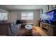 A well lit living room with tile flooring, a gray sectional, and a large television at 7126 N 19Th Ave # 122, Phoenix, AZ 85021