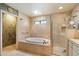 Bright bathroom featuring a soaking tub, glass-enclosed shower, and a skylight at 7746 E Bisbee Rd, Scottsdale, AZ 85258