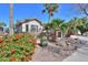 Beautifully landscaped home featuring stone accents, mature palms, a courtyard, and vibrant flowering bushes at 80 S Laura Ln, Casa Grande, AZ 85194