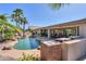Backyard pool with lush landscaping, an outdoor kitchen and covered patio at 80 S Laura Ln, Casa Grande, AZ 85194