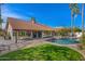 Expansive backyard featuring a covered patio, private pool with waterfall, and lush landscaping at 1101 N Peppertree Dr, Gilbert, AZ 85234
