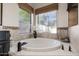 A luxurious bathtub is surrounded by decorative tilework and natural light from a large window at 1101 N Peppertree Dr, Gilbert, AZ 85234