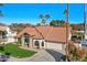 Beautiful single-story home with a red tile roof, an attached garage, manicured landscaping and mature palm trees at 1101 N Peppertree Dr, Gilbert, AZ 85234