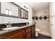 Bathroom featuring a double sink vanity and tiled walk-in shower with black accents at 15202 N 71St Dr, Peoria, AZ 85381