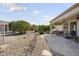 Expansive backyard featuring a stone patio, desert landscaping, and mature trees at 15434 W Big Sky Dr, Surprise, AZ 85374