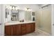 Bathroom featuring double sinks, a granite countertop, wood cabinets, and a glass-enclosed shower at 15434 W Big Sky Dr, Surprise, AZ 85374