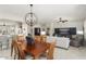 Open-concept living and dining area with wood table, light gray sofa, and adjacent kitchen with a breakfast bar at 15434 W Big Sky Dr, Surprise, AZ 85374