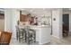 Kitchen with marble countertop breakfast bar, gray upholstered stools, and wood cabinetry with modern appliances at 15434 W Big Sky Dr, Surprise, AZ 85374