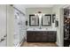 Bathroom featuring double sinks, walk-in shower with tile surround, and built-in storage at 16577 W Garfield St, Goodyear, AZ 85338