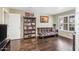 Living room with hardwood floors, large windows with shutters, futon and bookcase with decor at 16577 W Garfield St, Goodyear, AZ 85338