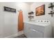 Bright laundry room with washer, dryer, ironing board, and decorative shelving at 1708 E Impala Ave, Mesa, AZ 85204