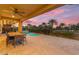 Inviting covered patio features a dining table and seating near a sparkling pool with beautiful sunset sky views at 175 E Santa Lucia Ln, Queen Creek, AZ 85140