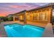 Twilight view of a stunning backyard with pool, covered patio, and lighting at 175 E Santa Lucia Ln, Queen Creek, AZ 85140